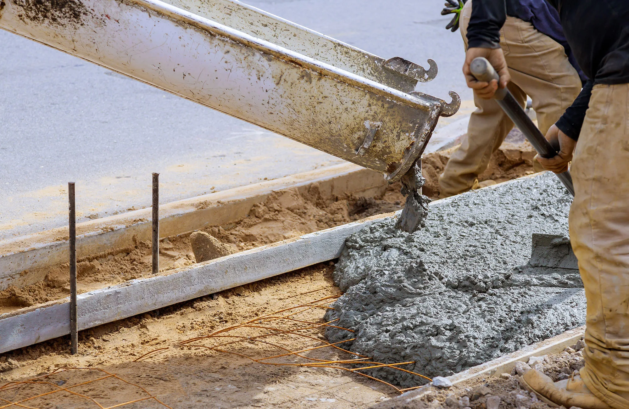 Concrete is poured into framing for a sidewalk.